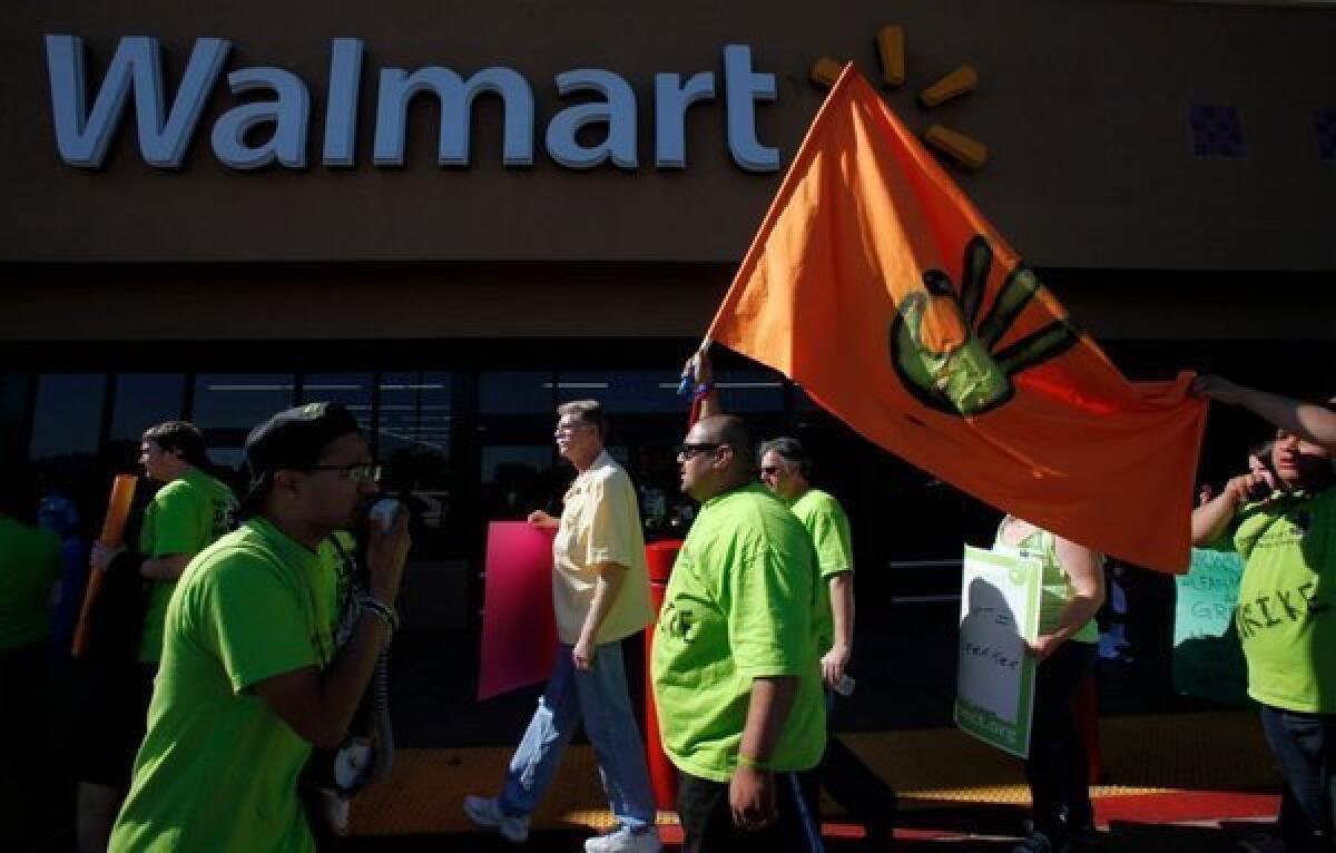 Workers march, pushing for better pay and working conditions, outside a Wal-Mart in Paramount. The big retailer is stepping up its Thanksgiving sales promotions.