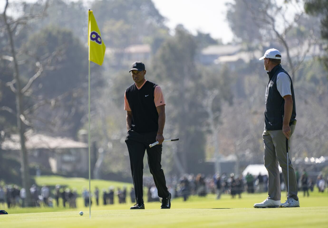 Tiger Woods looks at the flag depicting Kobe Bryant's No. 8 as he walks to mark his ball on the eighth green during the first round of the Genesis Invitational at Riviera Country Club on Feb. 13, 2020.