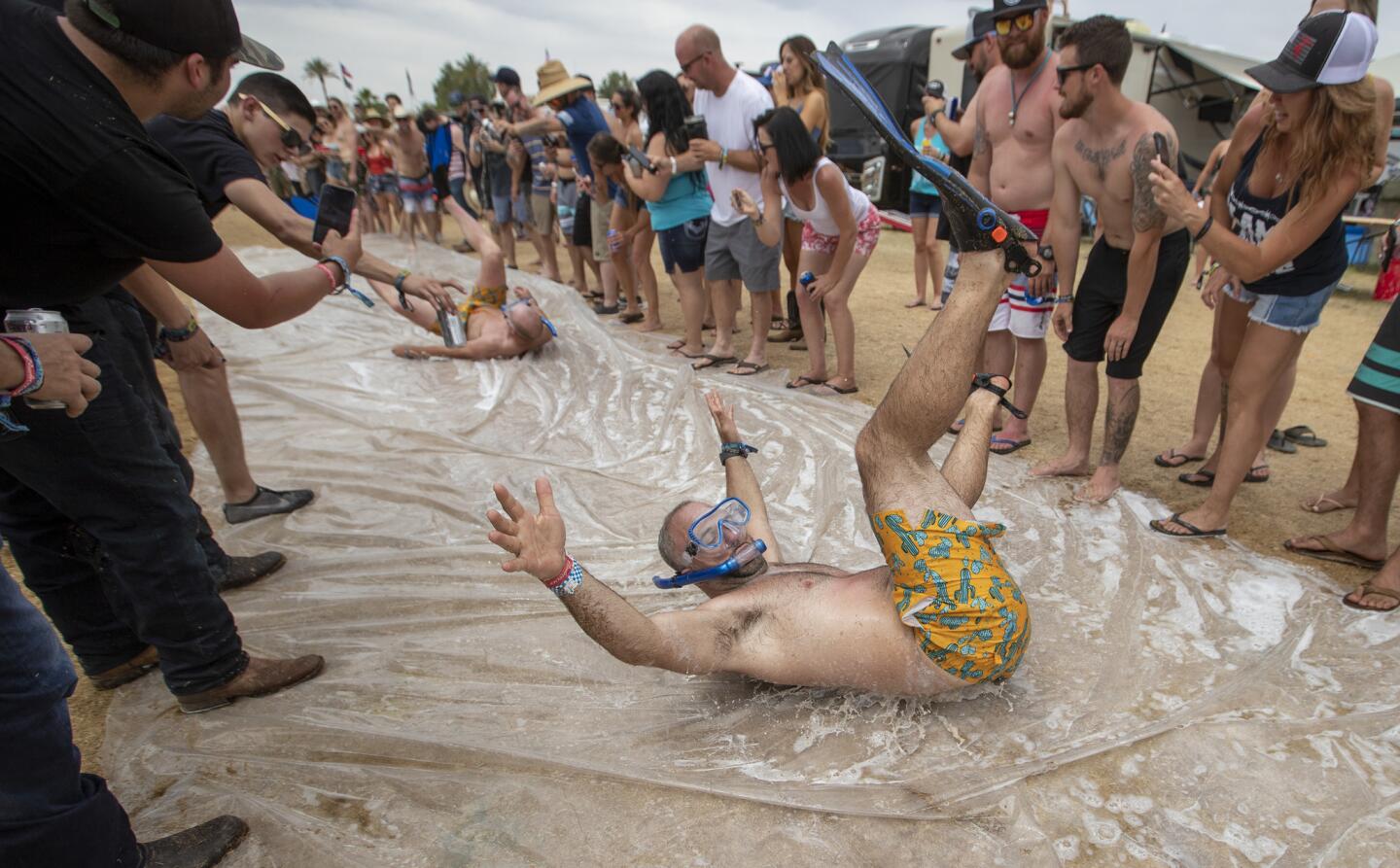 Before the bands started playing, people take turns on a giant slip-n-slide amid the crowd in the RV Resort on the final day of the three-day 2019 Stagecoach Country Music Festival.