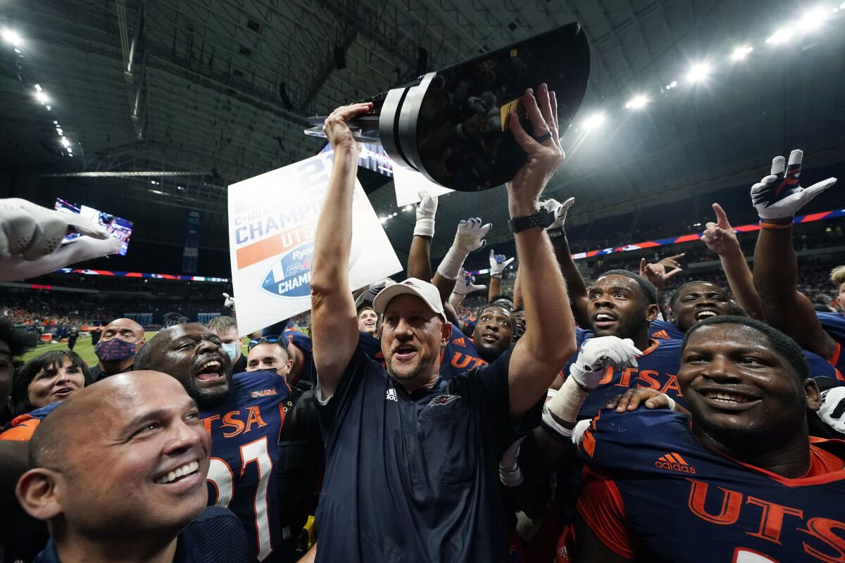UTSA head coach Jeff Traylor, center, holds the team's conference trophy as he and his team celebrate their win over UAB in an NCAA college football game, Saturday, Nov. 20, 2021, in San Antonio. (AP Photo/Eric Gay)