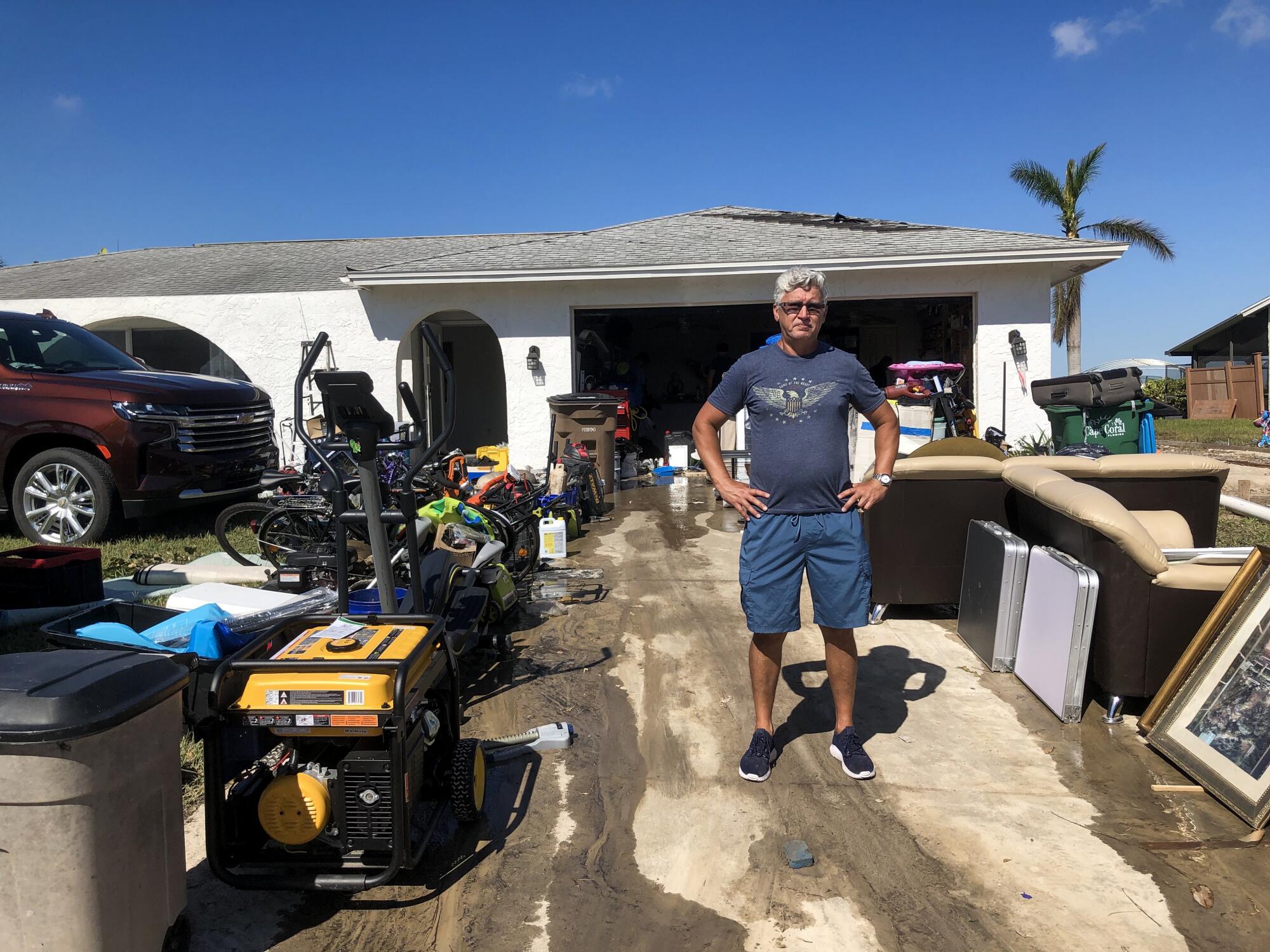 Ignacio Soto stands among some of his recovered possessions in front of his home