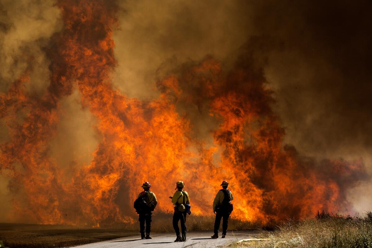 Bomberos observan las llamas del nombrado Incendio Apple en Cherry Valley, California, 