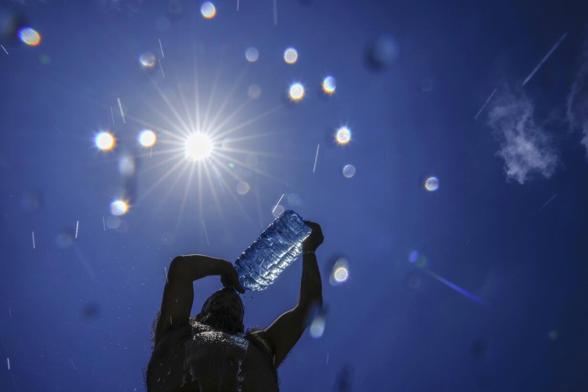 A man pours cold water onto his head to cool off in the sun.