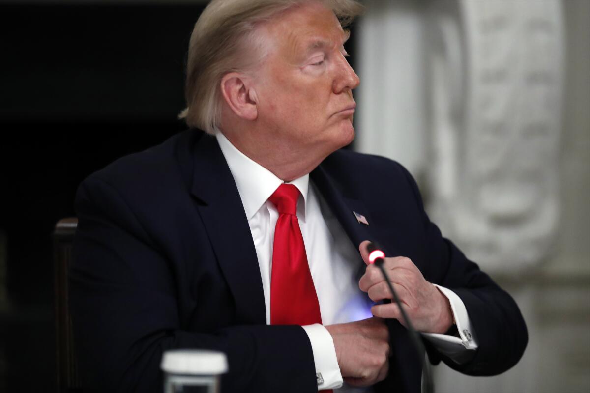 President Trump puts his phone back into his jacket during a roundtable with governors on June 18, 2020.