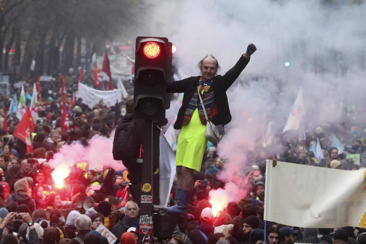 A man stands on a traffic light during a demonstration in Paris