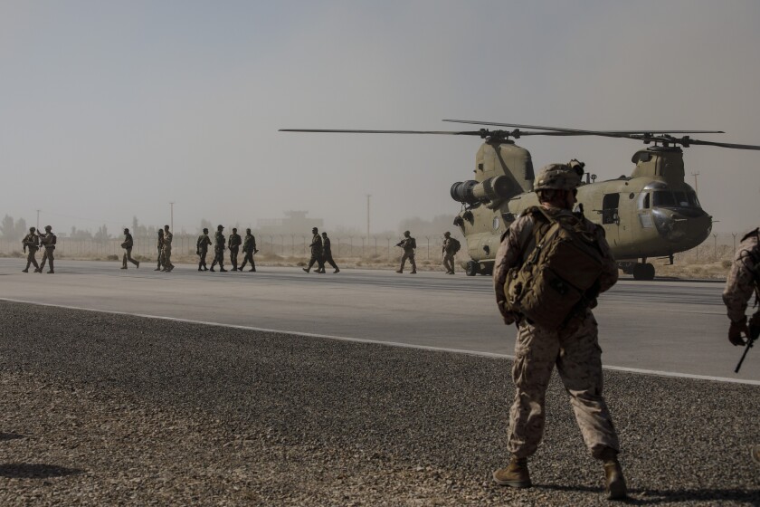 U.S. Marines disembark from a dual rotor military helicopter 