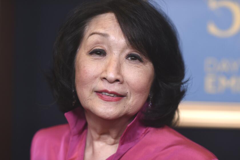 Connie Chung in a fushia pink blouse angling her head as she poses for pictures 