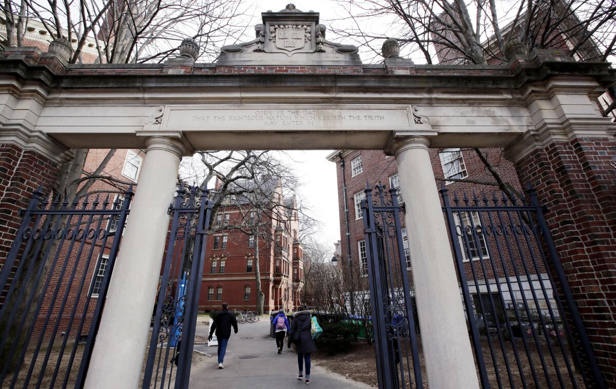 FILE - People walk through the gates leading to Harvard Yard, Dec. 13, 2018, at Harvard University in Cambridge, Mass. Students will be able to apply to Harvard University without submitting SAT or ACT scores for at least the next four years, the Ivy League school announced Thursday, Dec. 16, 2021, extending a policy many colleges have adopted during the pandemic and that a growing number are keeping for years to come. (AP Photo/Charles Krupa, File)