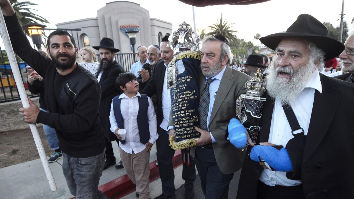 Howard Kaye, the husband of Lori Kaye, carries the new Torah as Rabbi Yisroel Goldstein, right, and other members of the Chabad of Poway celebrate its completion.