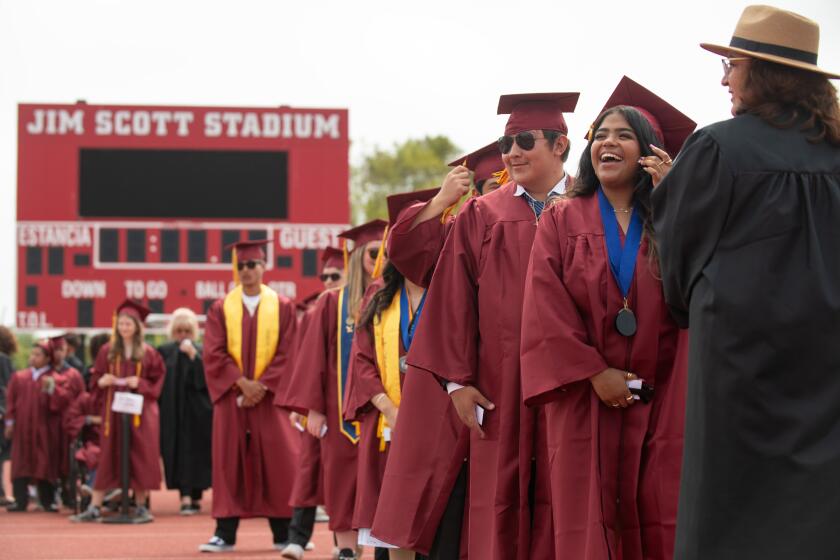 An Estancia High senior laughs before walking during her graduation ceremony at the Jim Scott Stadium in Costa Mesa Thursday.