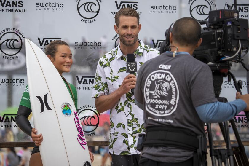HUNTINGTON BEACH, CALIF. -- WEDNESDAY, JULY 31, 2019: World Surf League broadcast commentator Ian Foulke, center, of San Clemente, interviews surfer Vahine Fierro, of Tahiti, after she won her heat during a live broadcast of the US Open of Surfing in Huntington Beach, Calif., on July 31, 2019. (Allen J. Schaben / Los Angeles Times)