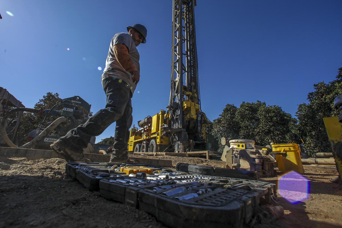 A man works on drilling a well on Setton Farms in Terra Bella, Calif.