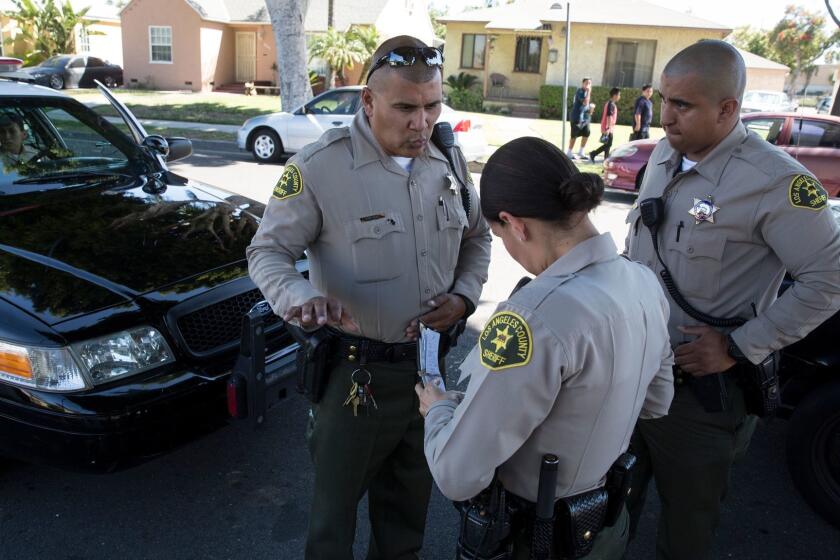 MAYWOOD, CALIF. -- TUESDAY, JUNE 27, 2017: Sheriff's deputy Marino Gonzalez, left, talks with deputies while investigating a disturbance in Maywood, Calif., on June 27, 2017. (Brian van der Brug / Los Angeles Times)