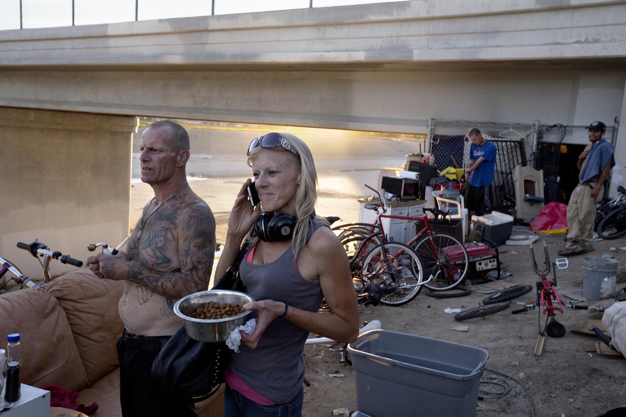 Kenneth Colato, 49, known as Rabbit, stands with Lauren, 33, in front of his home underneath a bridge along the L.A. River.