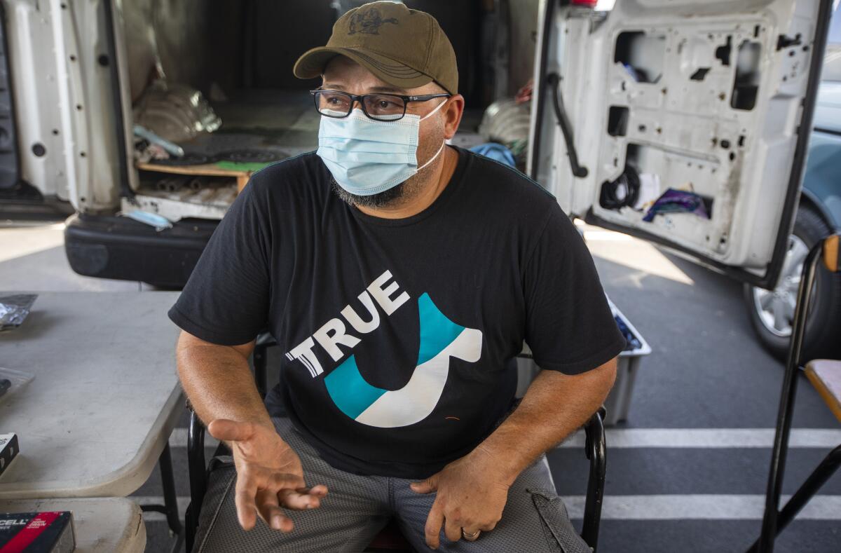 A man sits in a chair at a swap meet.