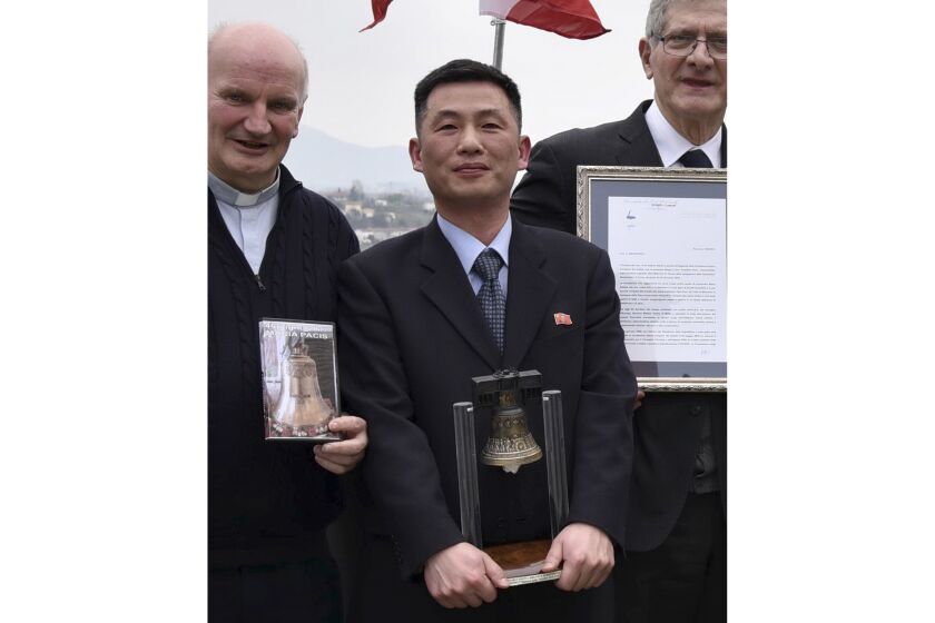 FILE - This March 20, 2018, file photo made available on Jan. 3, 2019, by the Parish of Farra di Soligo shows North Korea's acting Ambassador to Italy Jo Song Gil, center, holding a model of "Bell of Peace of Rovereto" during a cultural event on the occasion of a visit of the North Korean delegation to the Veneto region in San Pietro di Feletto, near Treviso, northern Italy. Jo, a senior North Korea diplomat who vanished in Italy in late 2018, lives in South Korea under government protection, lawmakers said Wednesday, Oct. 7, 2020. Also seen are don Brunone De Toffol, parish priest of Farra di Soligo, left, and Senator Valentino Perin, right. (Parish of Farra di Soligo via AP, File)