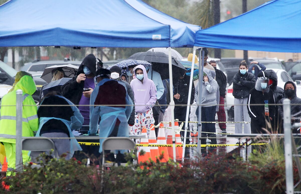 People line up in the rain for COVID-19 testing in the parking lot of Long Beach City College on Wednesday.