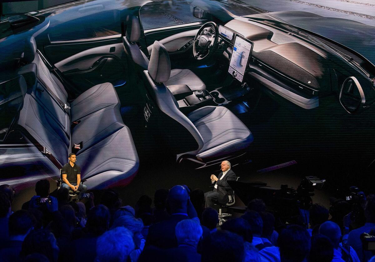 El CEO de Ford, James Hackett, a la derecha, devela el primer automóvil eléctrico de mercado masivo de la compañía, el Mustang Mach-E.