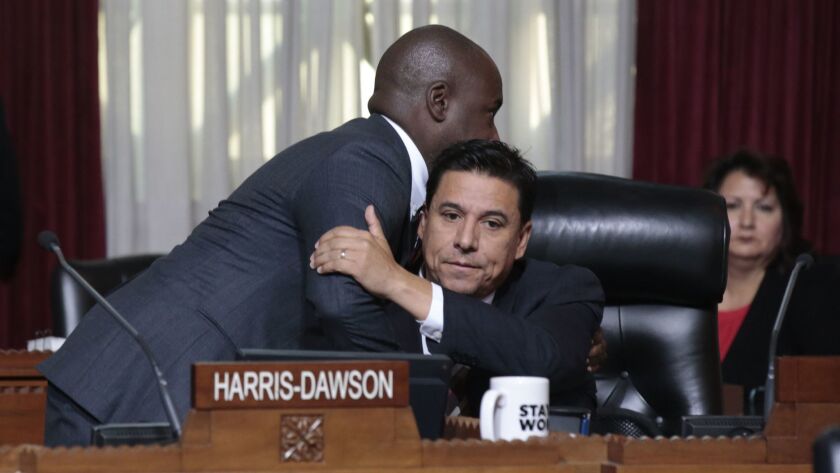 Los Angeles City Councilman Jose Huizar, right, hugs Councilman Marqueece Harris-Dawson during Huizar's first appearance on the council floor since his home and offices were raided by the FBI this month.