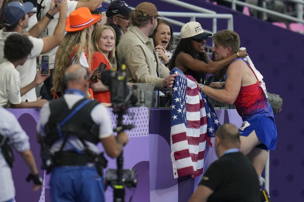 Hunter Woodhall leans into the stands and hugs his wife, Tara Davis-Woodhall, after winning the 400-meter T62 final