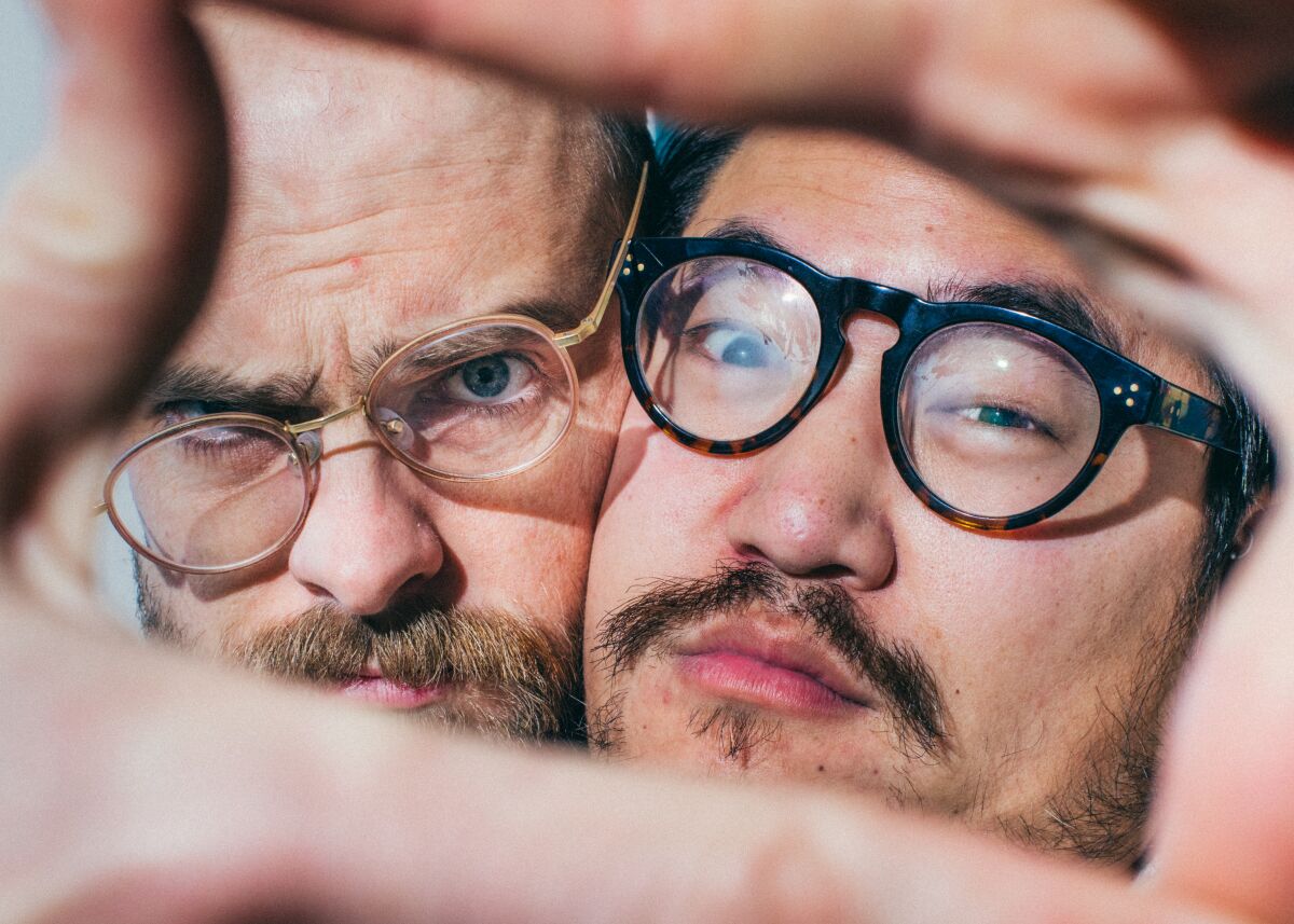 Two men smash their faces together as they look through a viewfinder-like finger square.