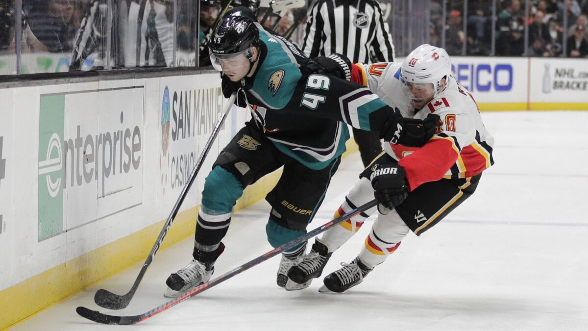 Ducks' Max Jones, left, moves the puck past Calgary Flames' Derek Ryan during the second period on Wednesday at the Honda Center.