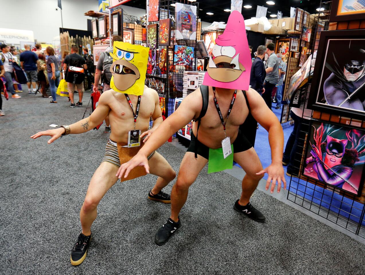 Costumed attendees wearing SpongeBob SquarePants character masks pose on the convention floor during opening day of the annual Comic-Con International in San Diego