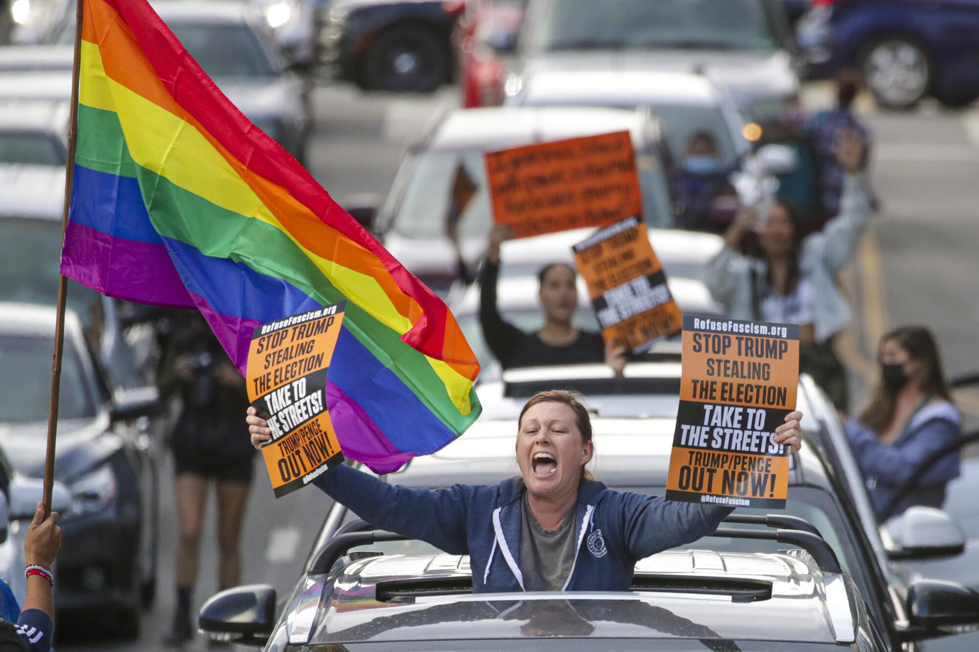 A person in a car sunroof brandishes signs in downtown L.A. 