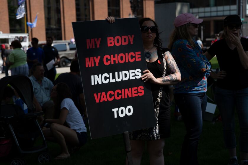 LANSING, MI - AUGUST 06: A woman holds a sign as she joins hundreds of demonstrators protesting against mandated vaccines outside of the Michigan State Capitol on August 6, 2021 in Lansing, Michigan. There were 44 counties in Michigan at high or substantial levels of community coronavirus transmission, according to the U.S. Centers for Disease Control and Preventions case and test positivity criteria as of August 5, 2021. (Photo by Emily Elconin/Getty Images)