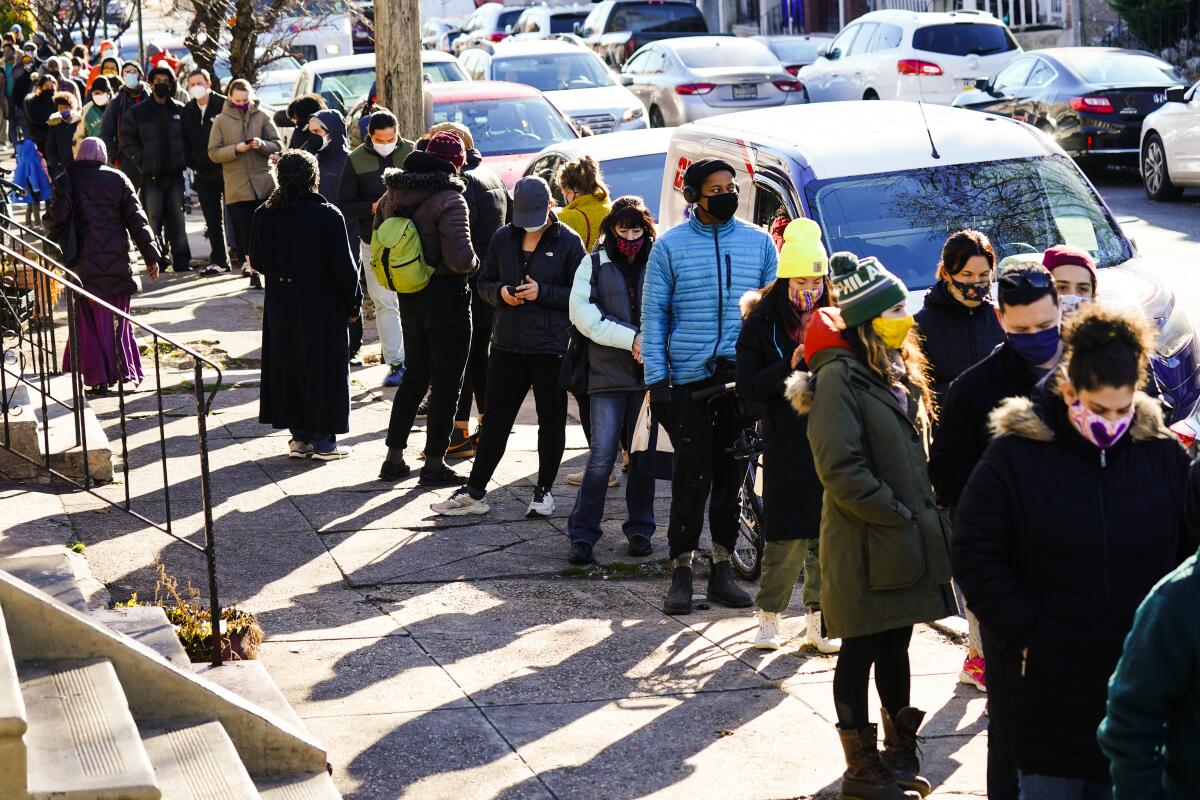 People wait in a line extending around the block to receive free at-home rapid COVID-19 test kits in Philadelphia.