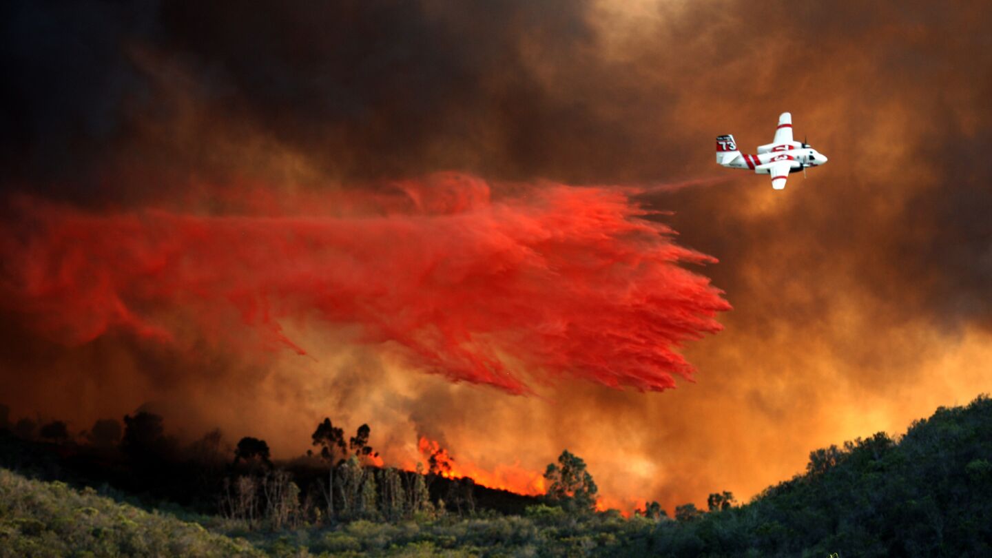 An airplane makes a fire retardant drop on a burning hill near in a fire that burned nearly 2,000 acres in northern San Diego County in May 2014. A 14-year-old girl convicted of starting the fire was sentenced Wednesday to 400 hours of community service.