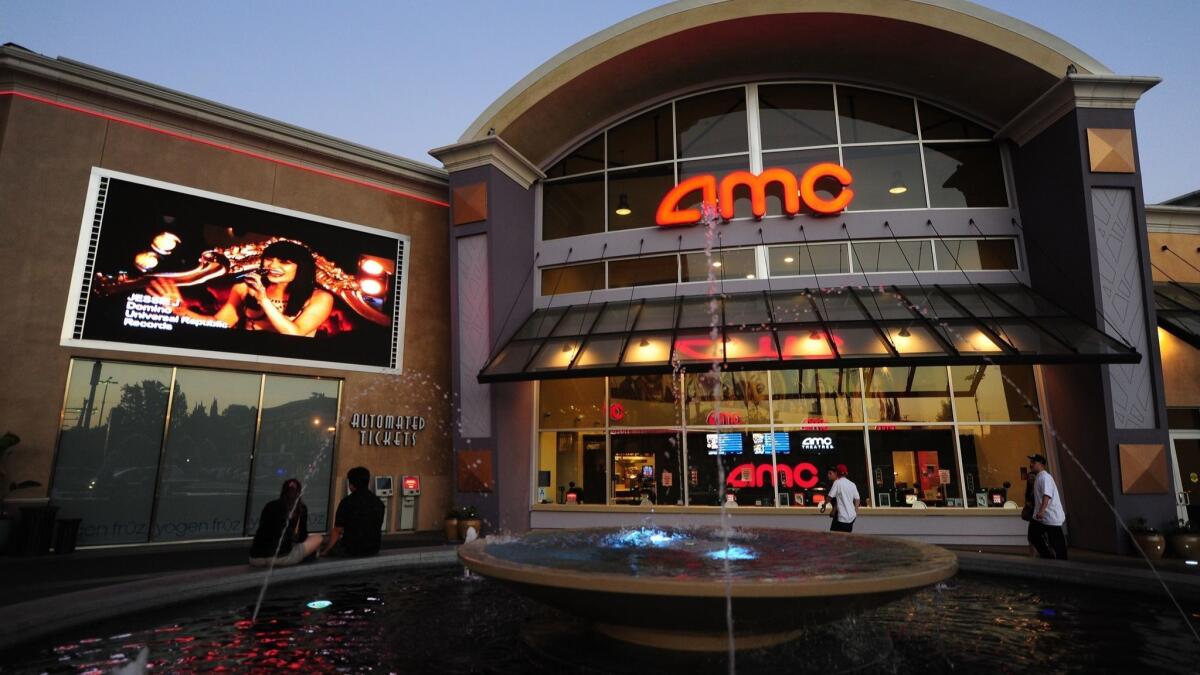 A couple watch a big screen outside movie theaters of the cinema chain AMC Entertainment.