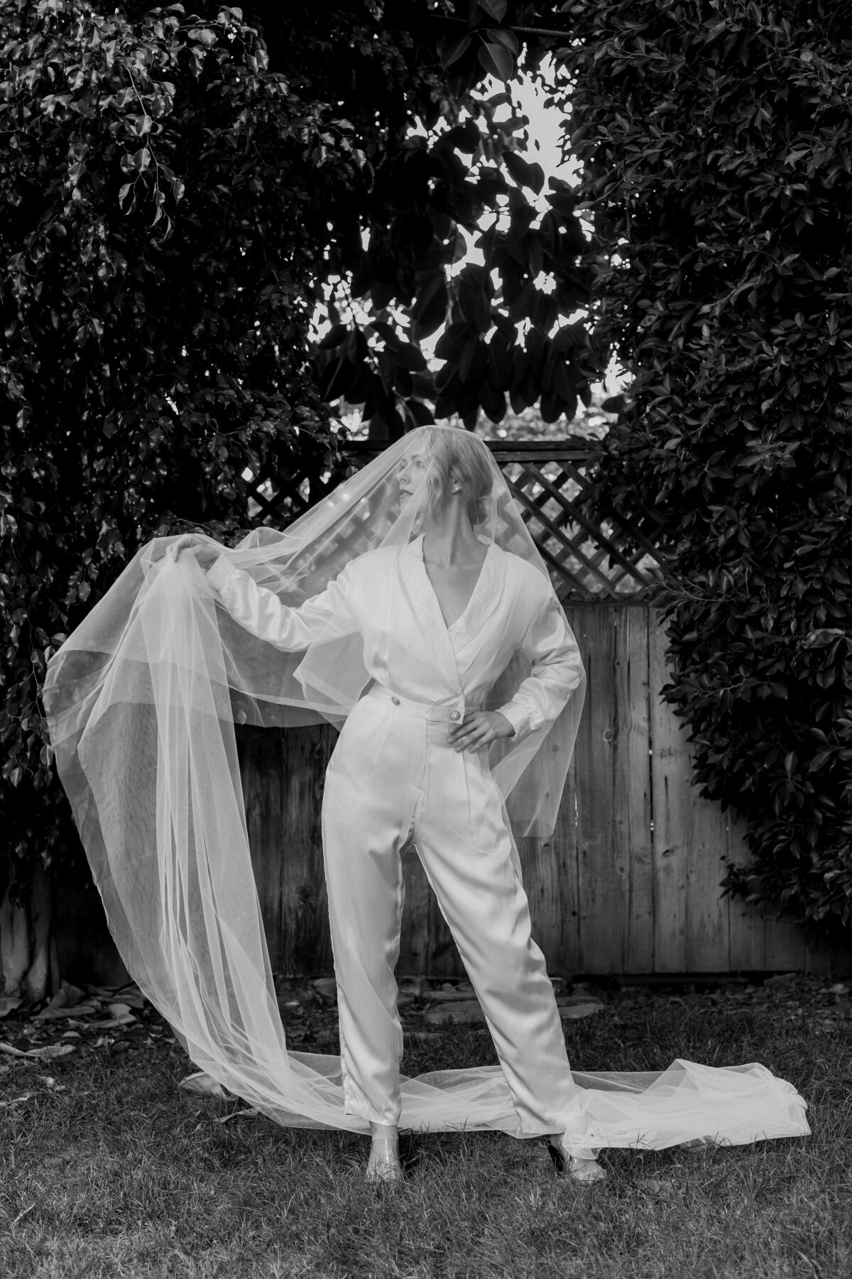 A model wears a white jumpsuit and bridal veil.
