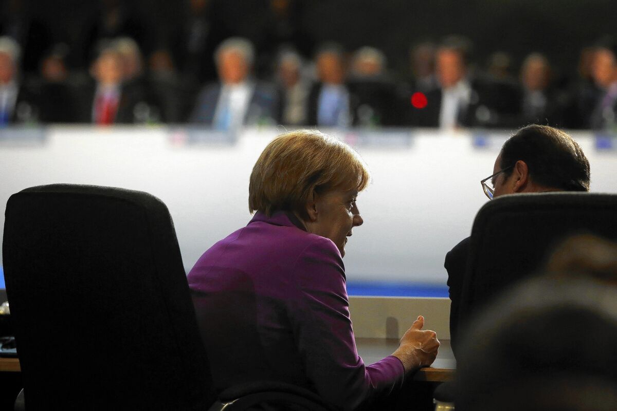 German Chancellor Angela Merkel speaks with French President Francois Hollande at a NATO meeting in Newport, Wales, on Sept. 5, 2014.