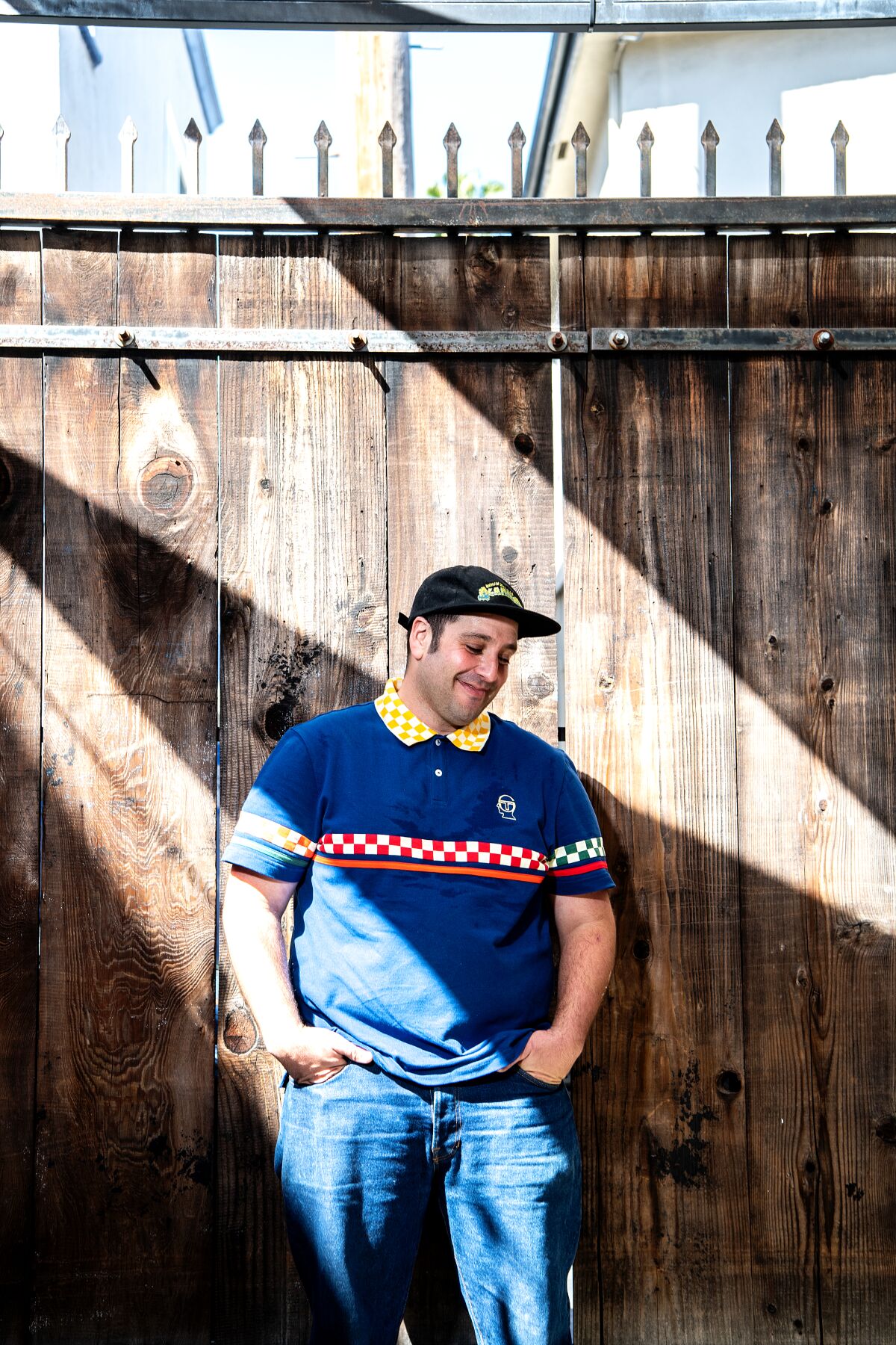 Chef Jesse Furman of Slammers Cafe leans against a wall of wooden planks.