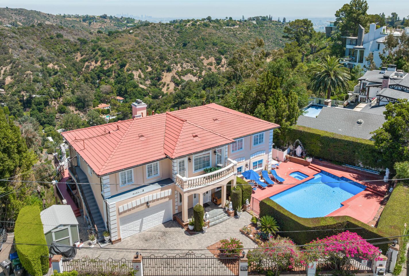 The 1980s home in an aerial view of the house, pool and surrounding greenery.