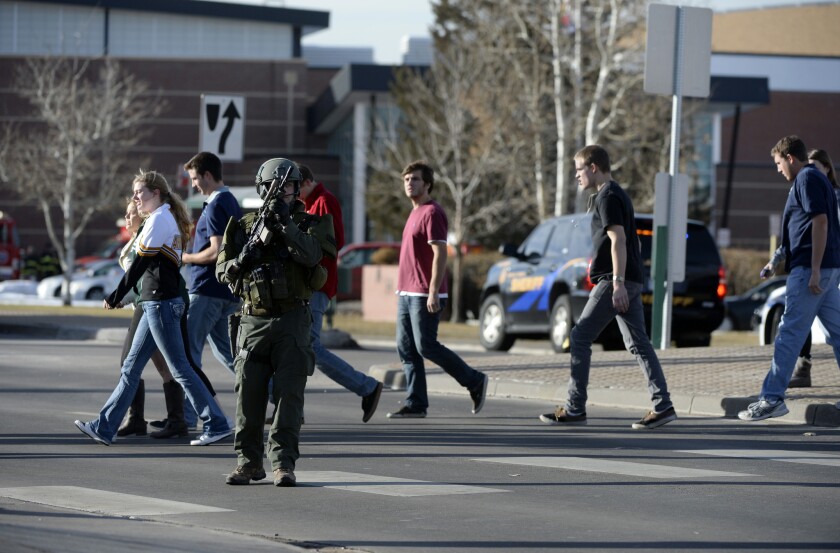 Students, escorted by armed police, are led out of Arapahoe High School after a shooting on the campus in Centennial, Colo.