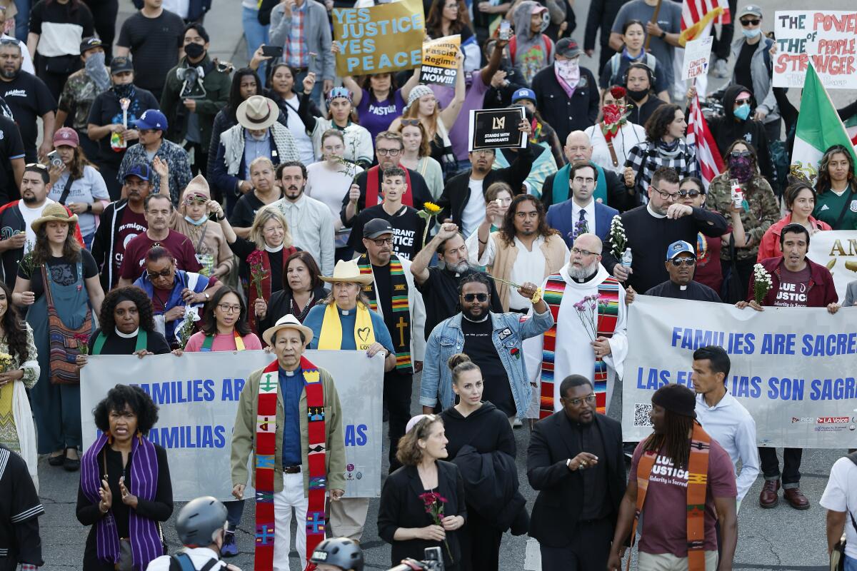 Members of the clergy lead a crowd down Temple Street on Tuesday after a prayer vigil at Grand Park.