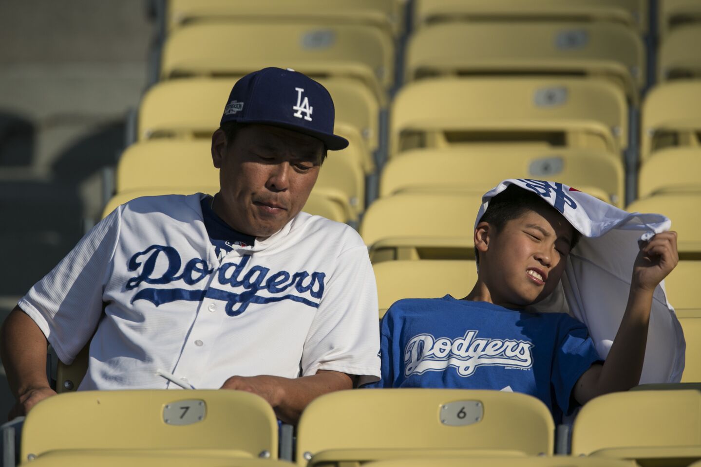 Darin Yoon, 12, endures the late afternoon sun as he sits with his father, John, at Dodger Stadium to watch the Dodgers and the Arizona Diamondbacks game.