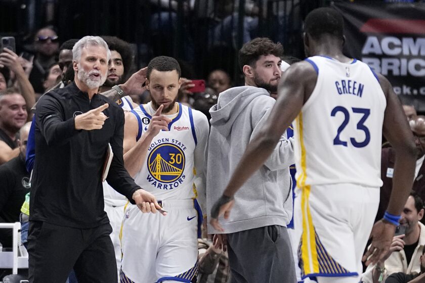 Golden State Warriors guard Stephen Curry (30) and Draymond Green (23), along with staff, celebrate a basket late in the second half of an NBA basketball game against the Dallas Mavericks, Wednesday, March 22, 2023, in Dallas. (AP Photo/Tony Gutierrez)