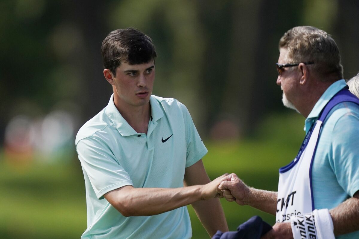 Davis Thompson fist bumps his caddie after finishing his round on the ninth green during the first round of the Rocket Mortgage Classic golf tournament, Thursday, July 1, 2021, at the Detroit Golf Club in Detroit. (AP Photo/Carlos Osorio)