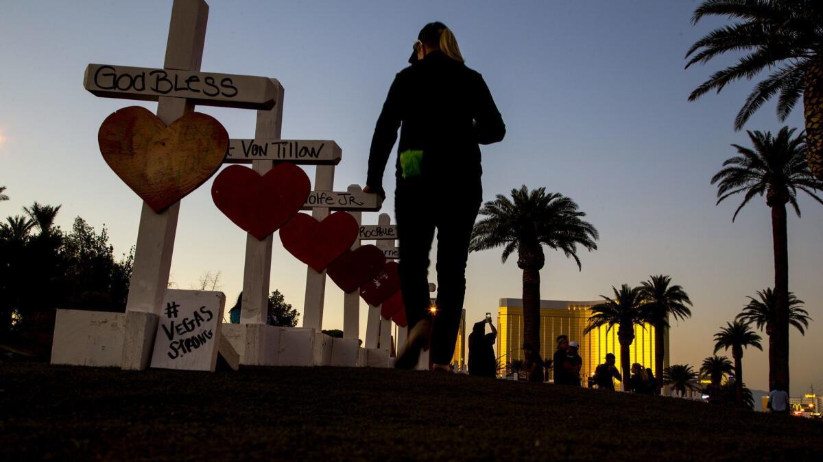 Carol-Ann Seitzinger, 62, of Las Vegas runs her hand over the top of each wooden crosses bearing the names of those killed during the mass shooting.
