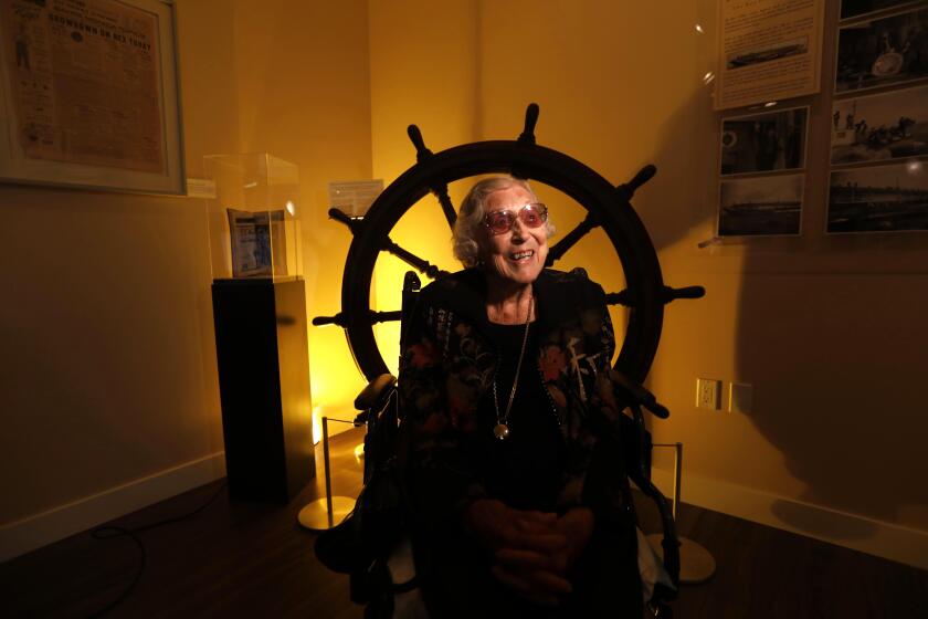 SANTA MONICA, CA - DECEMBER 10, 2019 - Florence Kinney, 107, sits in front of the steering wheel that once piloted The Rex ship which housed an offshore casino that now resides at the Santa Monica History Museum in Santa Monica on December 10, 2019. Kinney remembers the gambling boats and had family who gambled on them. In 1939, there was a standoff in the Pacific Ocean between the mobster Tony Cornero, owner of a group of gambling boats, and then Governor Earl Warren. The standoff eventually led to the closure of Cornero's gambling boats, including The Rex. It was a huge event in 1939, but it has faded from view. (Genaro Molina / Los Angeles Times)