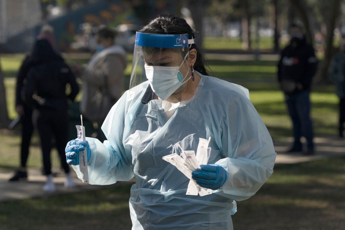 Medical assistant Leslie Powers carries swab samples collected from people to process them on-site at a COVID-19 testing site