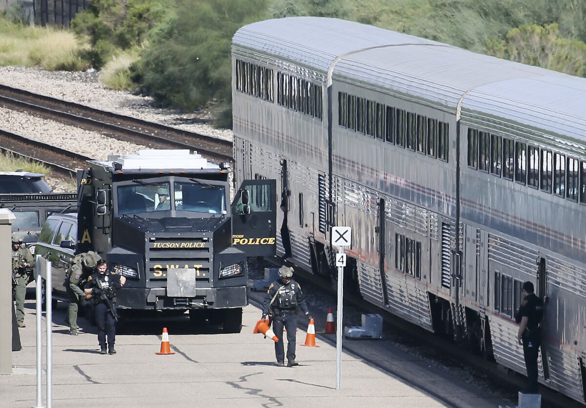 A Tucson Police Department SWAT truck is parked near the last two cars of an Amtrak train in downtown Tucson, Ariz., Monday, Oct. 4, 2021. One person is in custody after someone opened fire Monday aboard an Amtrak train in Tucson, Arizona, police said. The shooting happened just after 8 a.m. on a train parked at the station in the city's downtown. Authorities say the scene has been secured and no threat remains. (Mamta Popat/Arizona Daily Star via AP)