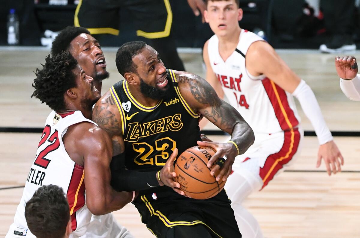 Lakers forward LeBron James is fouled by Miami Heat forward Jimmy Butler while driving to the basket.