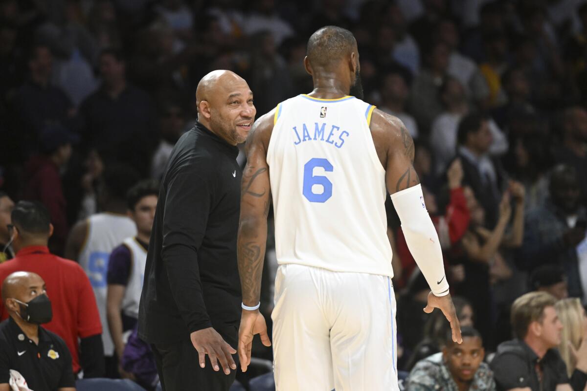 Lakers coach Darvin Ham talks with forward LeBron James along the sideline.