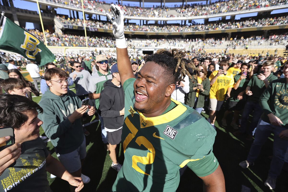 Baylor offensive lineman Mose Jeffery celebrates with fans who stormed the field after defeating Oklahoma in an NCAA college football game, Saturday Nov. 13, 2021, in Waco, Texas. (Ernesto Garcia/Waco Tribune-Herald via AP)