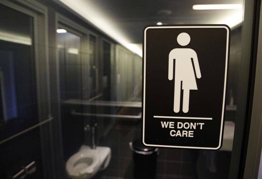 FILE - In this May 12, 2016, file photo, gender free sign hangs outside a restroom at 21c Museum Hotel in Durham, N.C. A 3 1/2-year ban on local ordinances aimed at protecting LGBT rights in North Carolina expired Tuesday, Dec. 1, 2020, prompting gay rights groups to urge the passage of such measures. Democratic Gov. Roy Cooper agreed to the moratorium in March 2017 in exchange for GOP lawmakers agreeing to do away with portions of a “Bathroom Bill” that Republicans had approved a year earlier.(AP Photo/Gerry Broome, File)