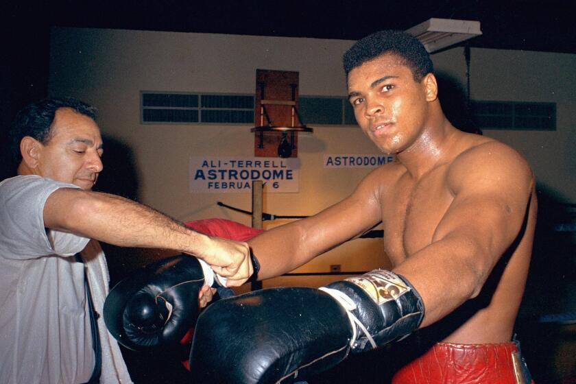 FILE - In this February 1967, file photo, Muhammad Ali gets his gloves laced by trainer Angelo Dundee.